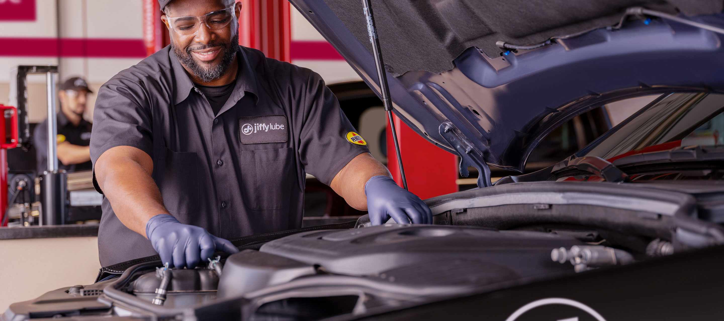 A Jiffy Lube technician working on a car.