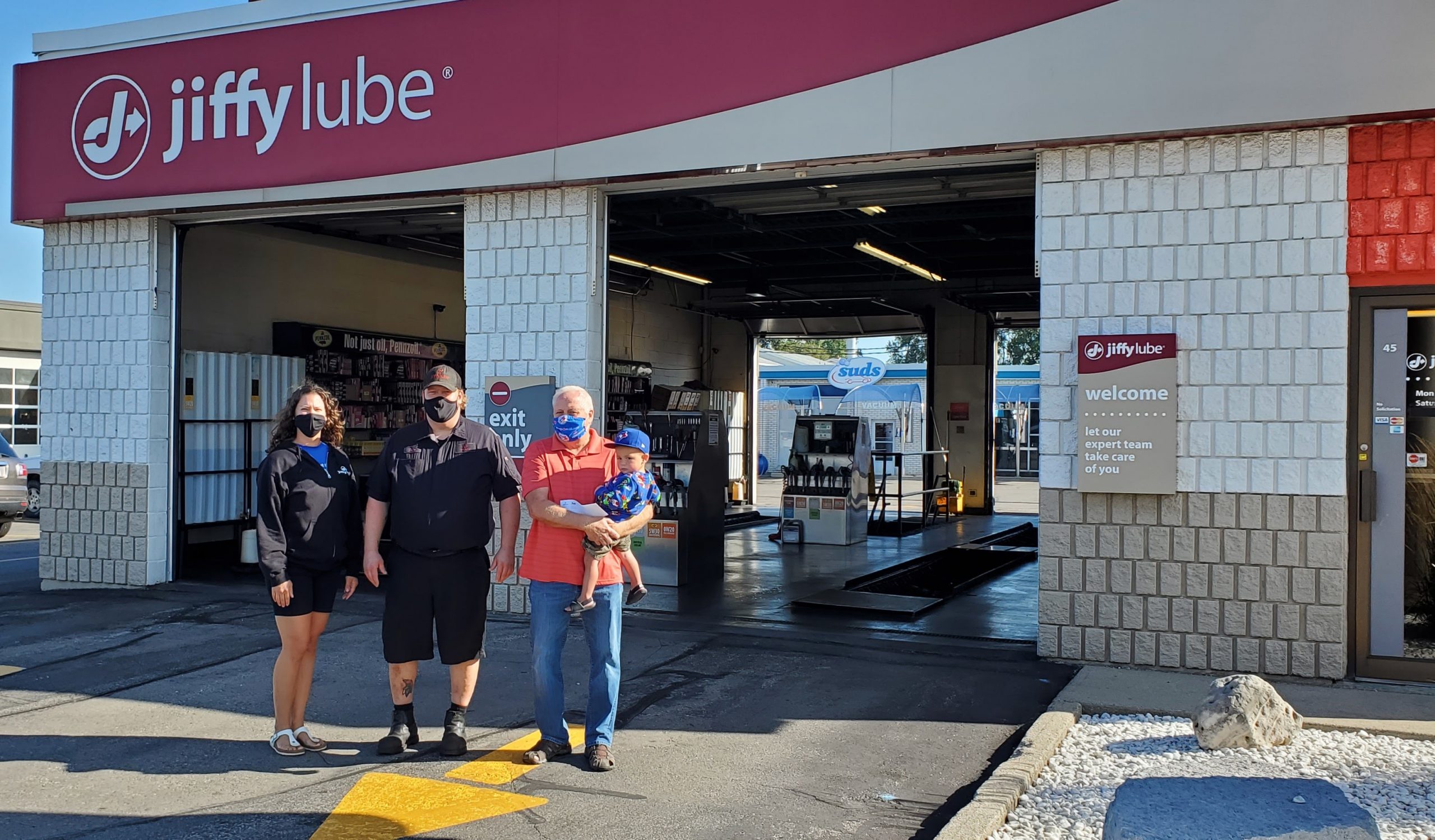 Winner from Jiffy Lube's 20th Anniversary Contest receiving her prize in front of a Jiffy location