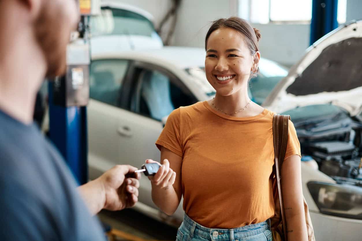 happy woman receiving car keys after vehicle maintenance